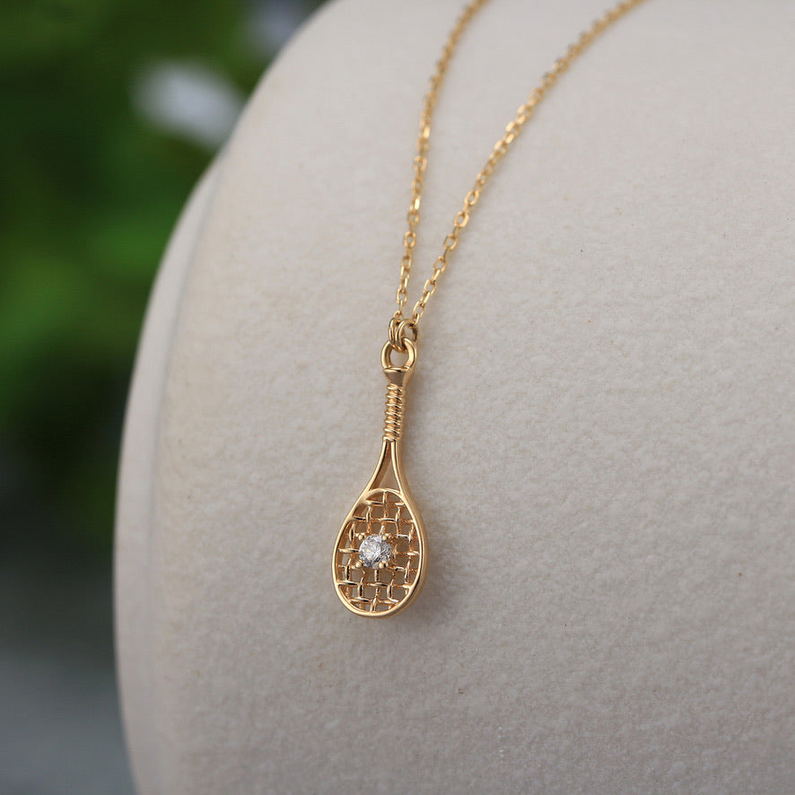 Solid Gold and Diamond Fine Tennis Necklace featuring a 15mm solid gold and detailed tennis racquet set with a brilliant diamond 'ball' in the center.