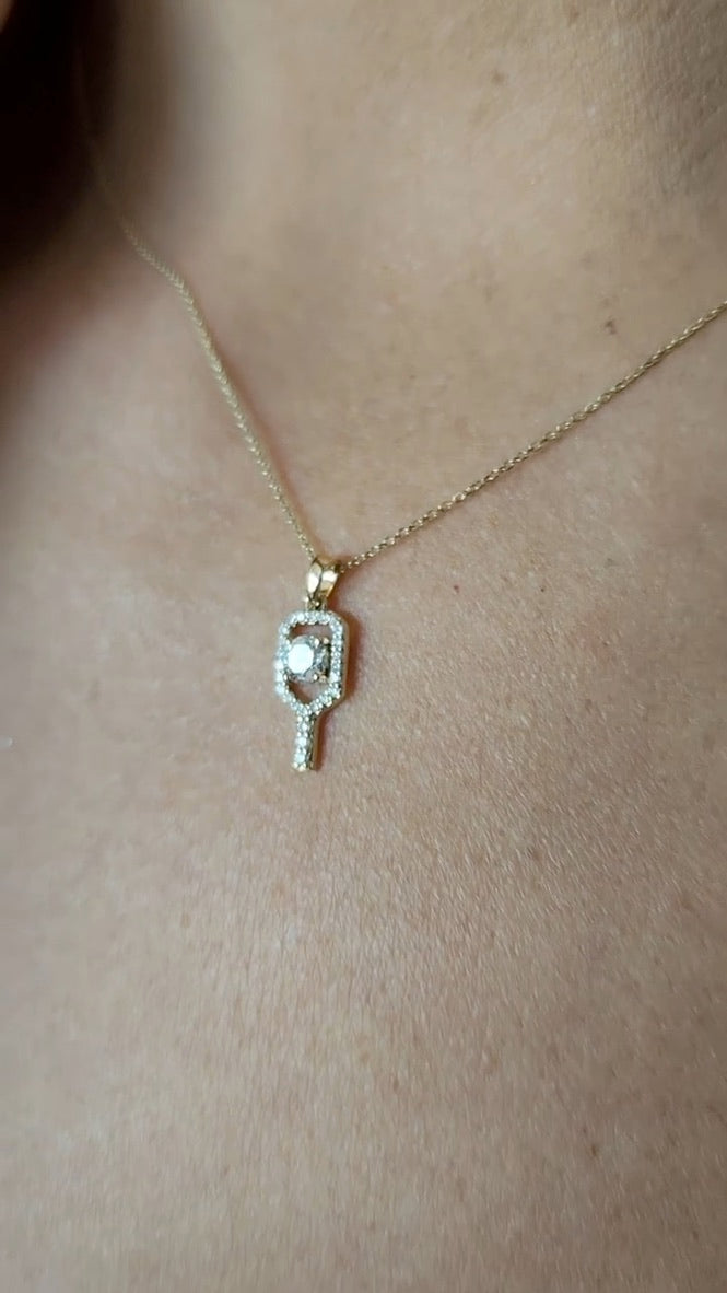 Gold  and diamond pickleball necklace with a pendant on a person's neck