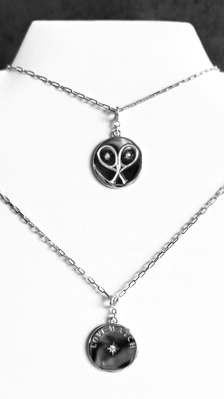 Chic Silver Tennis Heart Disc Necklace featuring  double sided pendant charm with 2 racquets creating a 'heart' with impact crystal inside each and our LoveMatch insignia on the reverse with a sparkling crystal center. Hangs from a chic, modern paper clip style chain - 16" with a 2" extender. 