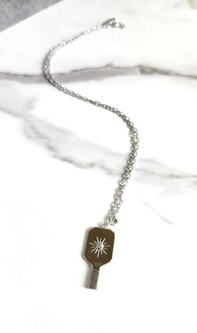 Silver Pickleball Grande Paddle Pendant Charm. This elegant charm features a realistic pickleball paddle in a Sterling Silver charm with a crystal-centered starburst design. Spring clip allows you to attach this to your favorite necklace or bracelet, or anywhere you can think of!