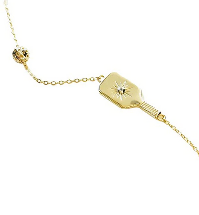 Pickleball The Dainty Dinker Starburst Mini Gold Necklace. Made from 14k gold over sustainably sourced sterling silver.  Top quality CZ stone with starburst 'impact' is set in the center of the paddle, and the pickleball charm sits further up the necklace. We have created a modern dainty clip chain for the necklace, and have added 2" of extender chain so you can wear this between 15" and 17".
